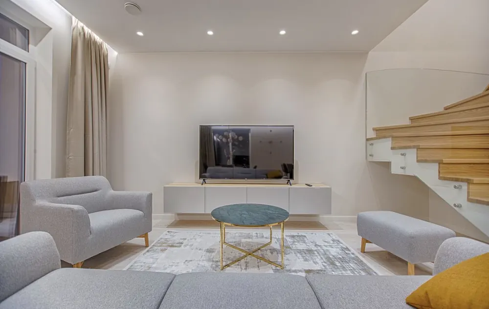 Salón a doble altura con escalera de madera volada y techo con iluminación indirecta
